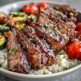 Golden roasted vegetables and tender steak rest on fluffy rice in a hearty Sheet Pan Steak and Veggie Bowl.