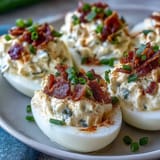 Cream cheese-stuffed deviled eggs topped with jalapeño slices and smoky bacon crumbles.