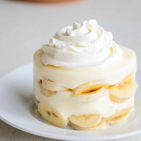 Creamy layers of banana pudding, showcasing sweet vanilla wafers and ripe banana slices with whipped topping.