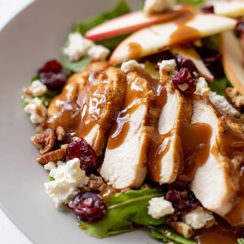 Golden caramel-pecan dressing drizzled over a hearty Caramel Apple Chicken Salad, garnished with crumbled goat cheese and dried cranberries.
