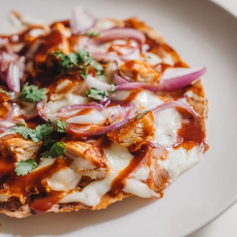 A crispy golden BBQ chicken flatbread fresh from the oven, topped with shredded grilled chicken, sweet red onions, gooey mozzarella, and a drizzle of tangy BBQ sauce.
