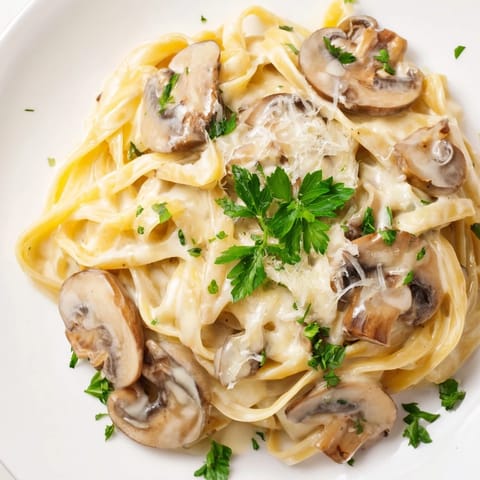 A steaming plate of Creamy Mushroom Alfredo garnished with fresh parsley and extra Parmesan on a rustic table.