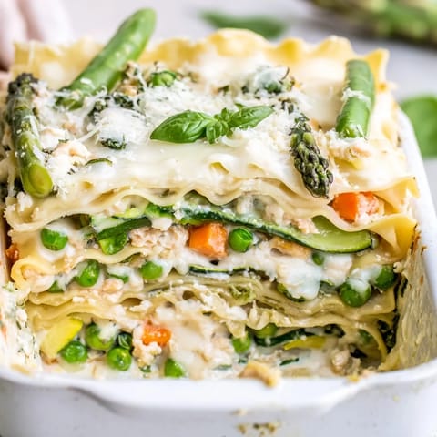 Golden-brown Spring Veggie Alfredo Lasagna bubbling from the oven, layered with no-boil noodles, creamy light Alfredo sauce, and a vibrant mix of asparagus, sugar snap peas, and spinach.
