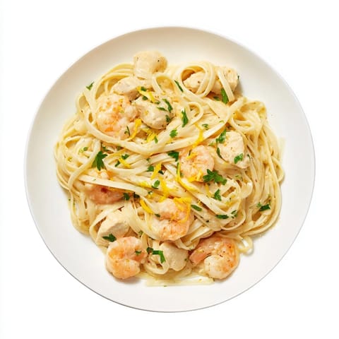 Savory Lemon Garlic Shrimp & Chicken Pasta plated with fresh parsley and lemon wedges, ready to be served as a vibrant Italian-American weeknight dinner.