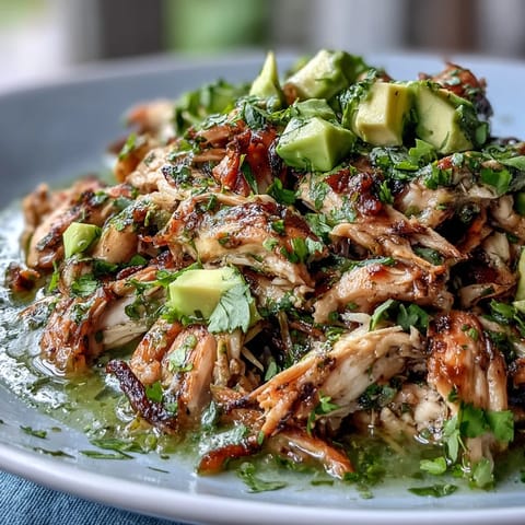 Tender shredded chicken simmered in bright, tangy tomatillo-chile sauce, garnished with creamy avocado and fresh cilantro.