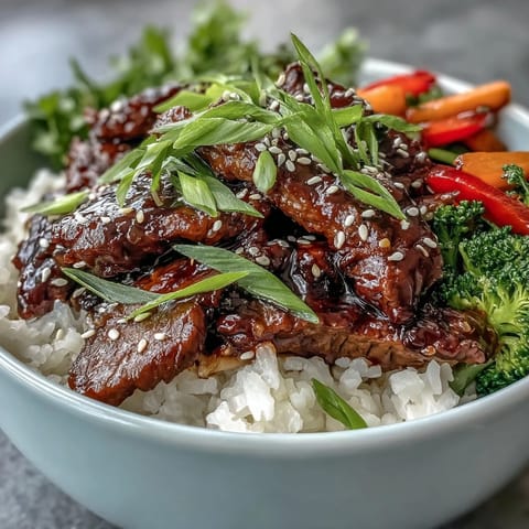Steaming bowls of Teriyaki Beef Bowl with fluffy rice, crisp broccoli, and carrots glazed in sweet sauce.