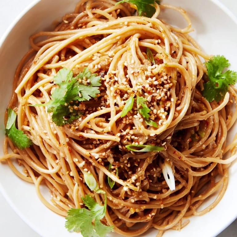 A close-up view of vibrant Spicy Sesame Noodle Salad with sesame seeds and herbs.  