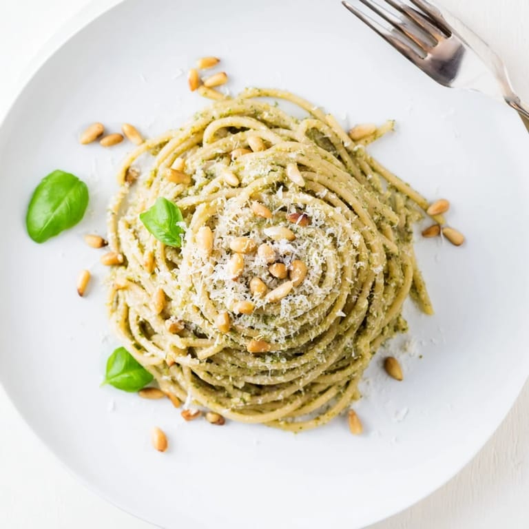A serving of Creamy Sunflower Seed Pesto Pasta plated beside a glass of white wine, perfect for a vegetarian weeknight dinner.