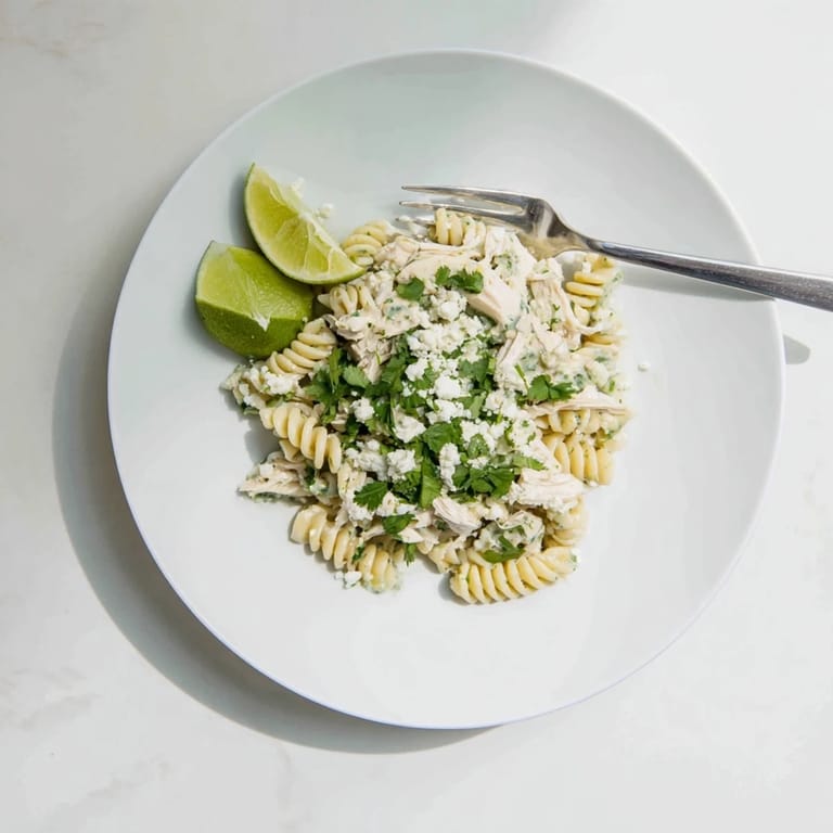 A fresh, colorful bowl of Cilantro Lime Chicken Pasta with shredded chicken, creamy green sauce, and crumbled feta.