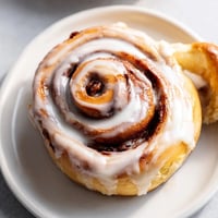 Warm, glazed cinnamon rolls glistening, perfect for a cozy breakfast or brunch treat.