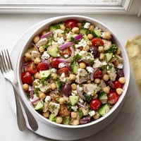 Brightly colored Mediterranean Chickpea Chicken Salad with juicy diced chicken, creamy crumbled feta, and Kalamata olives on a rustic serving platter.  