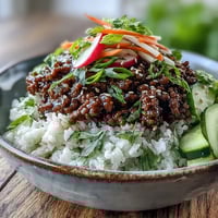 Savory Korean Ground Beef Bowl with jasmine rice, topped with tangy quick-pickled carrots and cucumbers for a vibrant weeknight meal.
